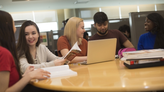 Five students share a table for completing course work