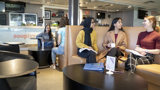 Three students share a table at the Soupbar for lunch