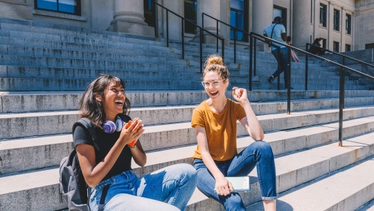 Female students sitting outside on steps